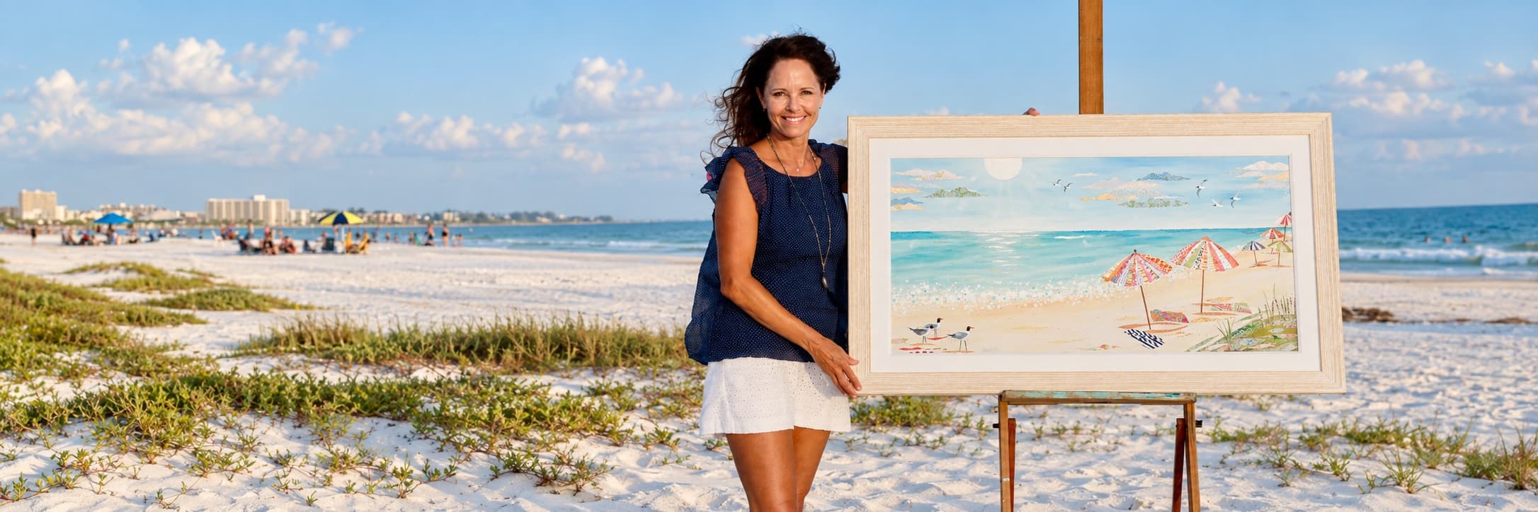 Jennifer Peck on a Florida beach beside a framed beach painting on an easel