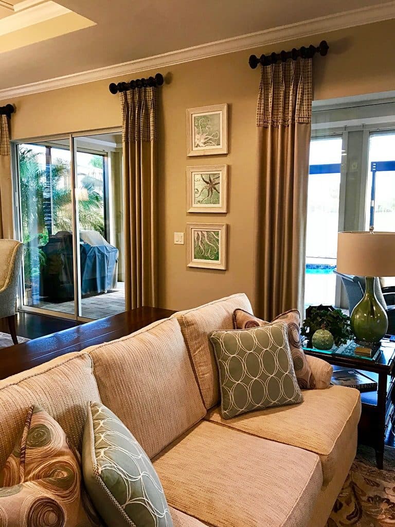 Three small framed sea-life prints stacked beside tall curtains in a living room