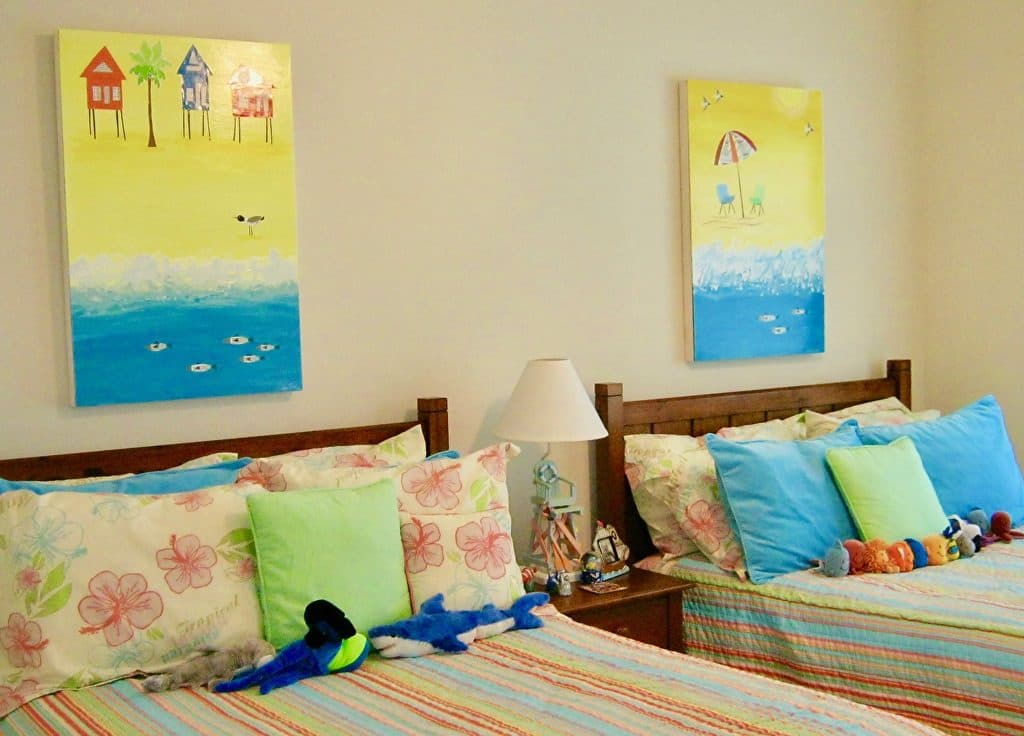 Two beach-house collages above twin beds with striped quilts