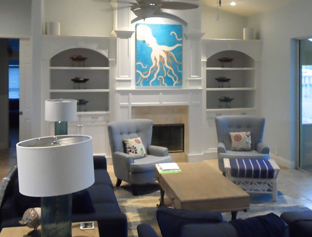 An octopus collage over a white fireplace flanked by built-in shelves