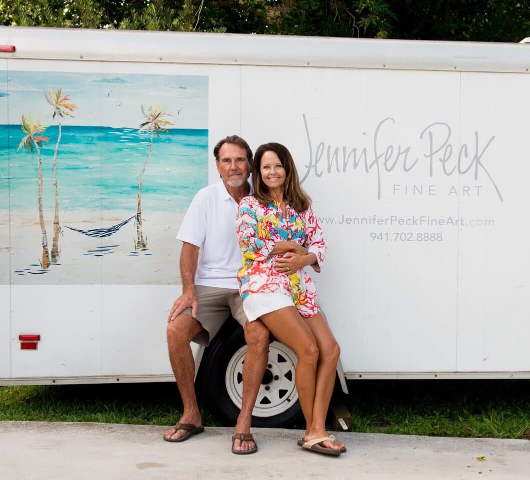 Jennifer and Steve sitting on the step of the white art trailer