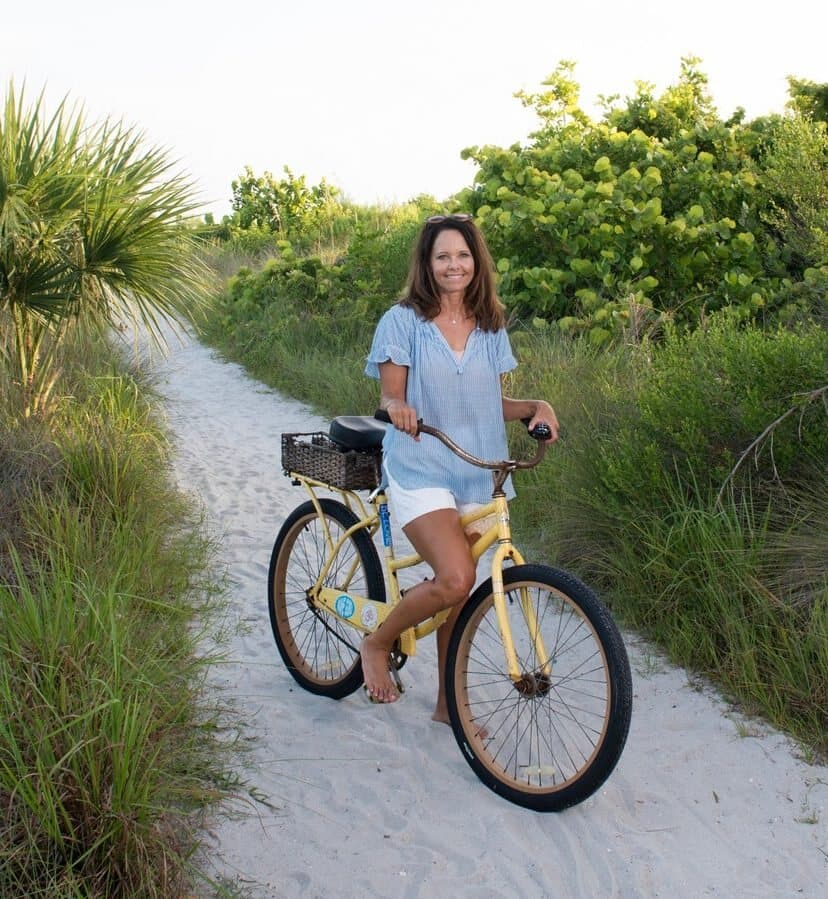 Jennifer with her yellow beach cruiser on a sandy path through the sea oats