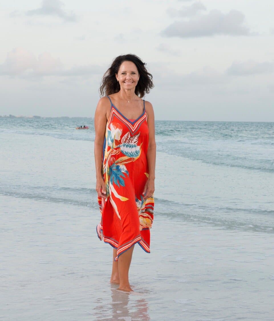 Jennifer Peck walking in the Gulf shallows in a red dress