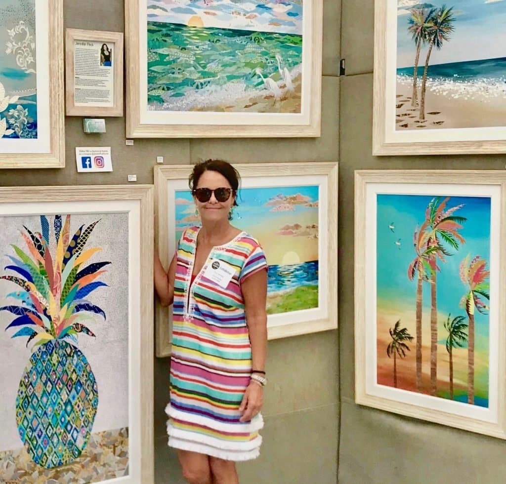 Jennifer at the booth beside a framed pineapple collage and a wall of palms