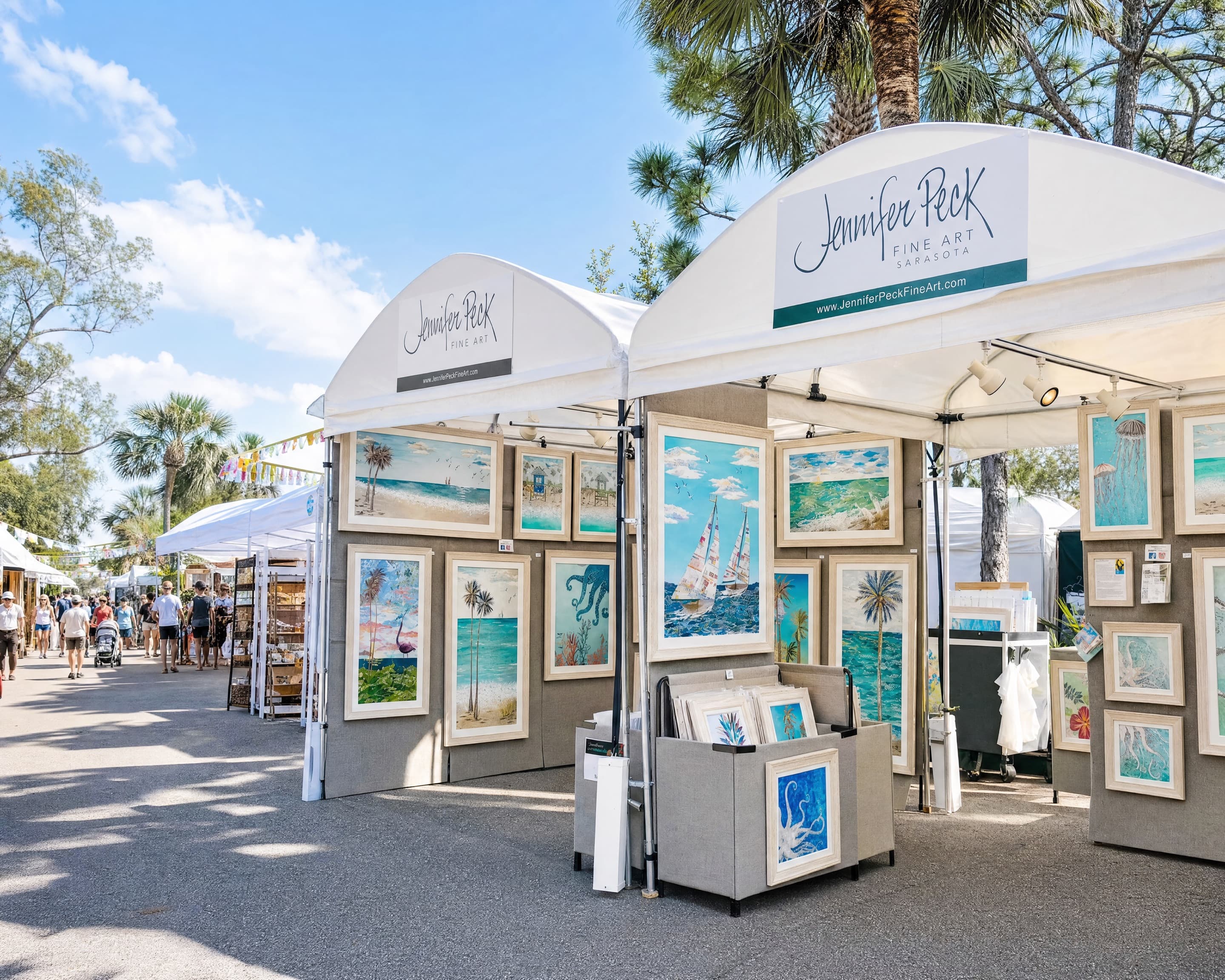 Jennifer Peck's white festival tents hung with framed coastal artwork, on a sunny festival street