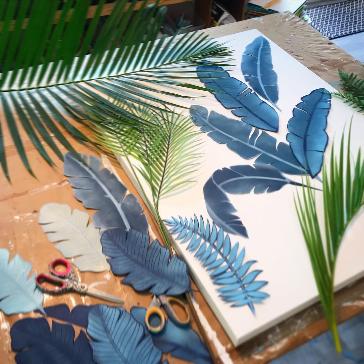 A fresh palm frond on the table beside its hand-cut paper twins