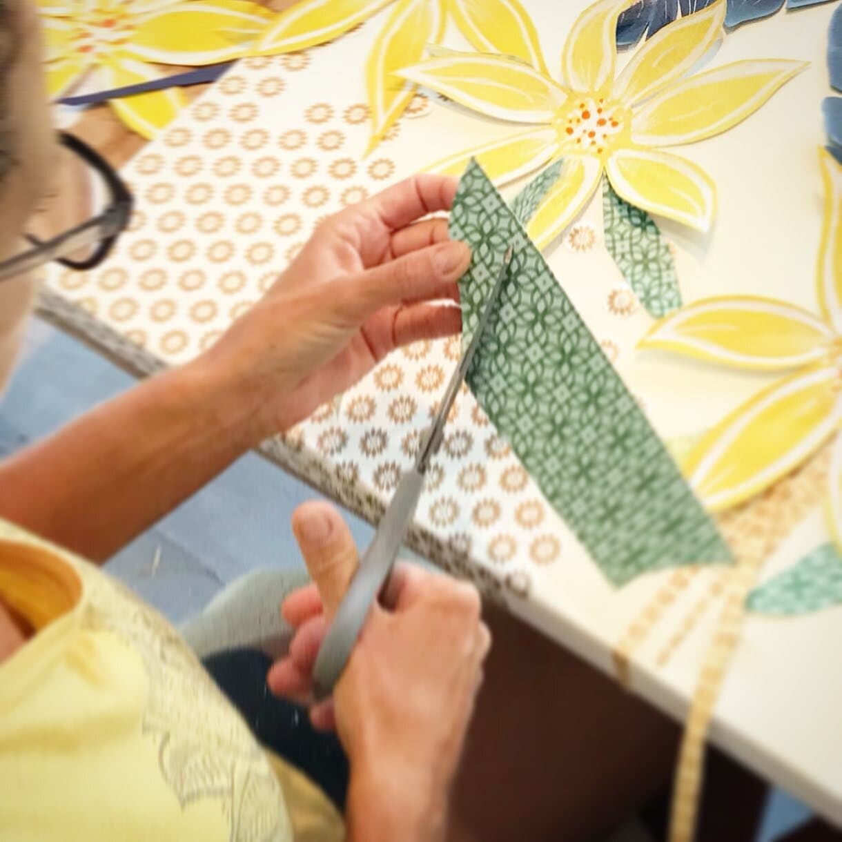 Jennifer's hands cutting a leaf shape from patterned green paper