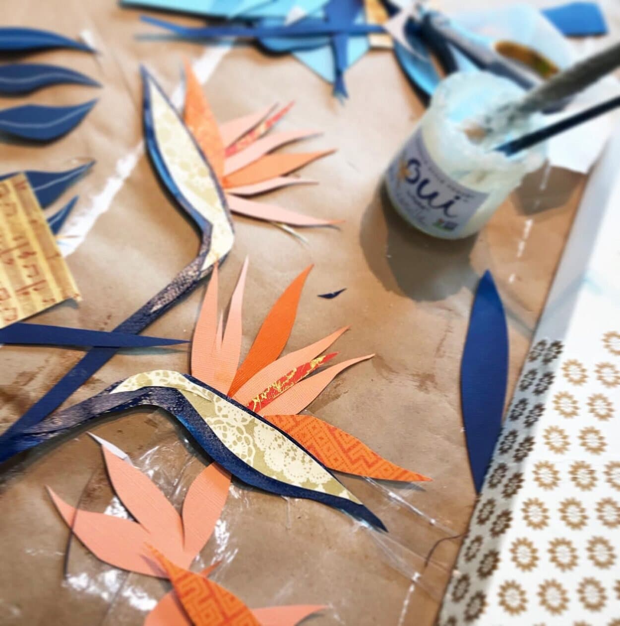 Bird of paradise shapes being glued and layered on the panel