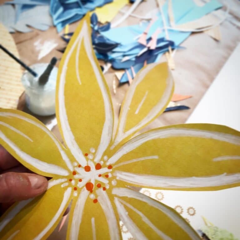 Painting fine white details onto a yellow paper flower by hand