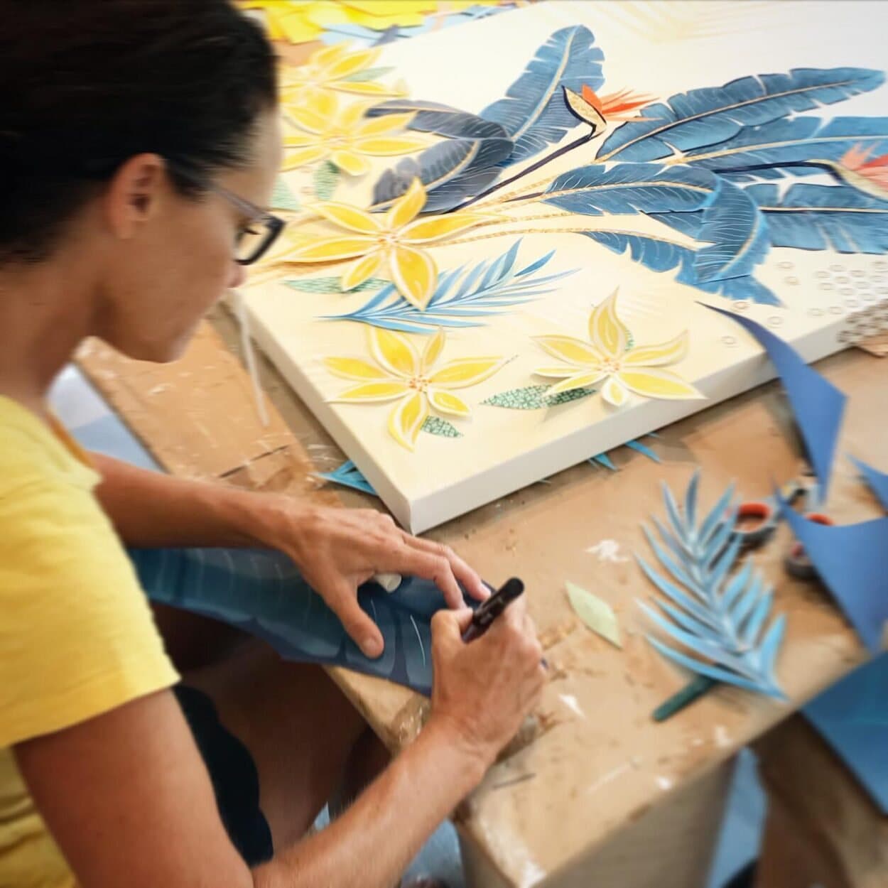 Jennifer at the studio table working on a large canvas