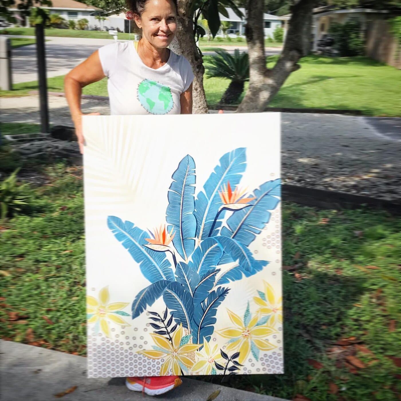 Jennifer smiling and holding the finished bird of paradise canvas outdoors