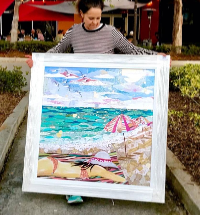 A collector holding a large framed beach-umbrella collage