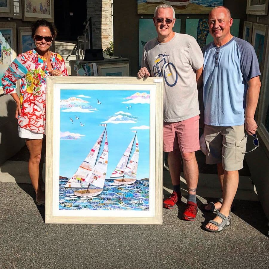 Jennifer with two collectors and a framed sailboat piece at the show