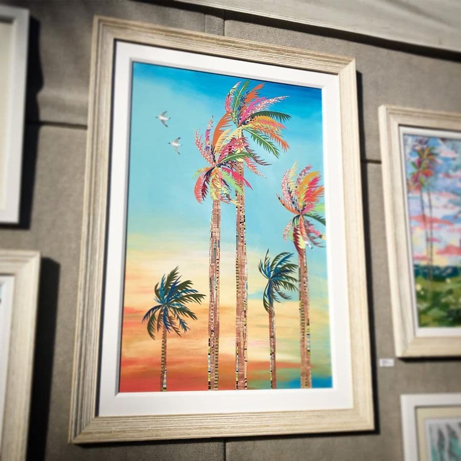 A tall framed palms-at-sunset piece in the booth
