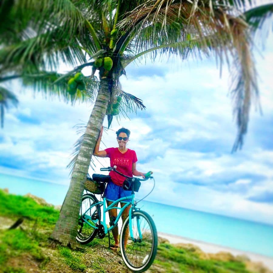Jennifer with her bike under a coconut palm