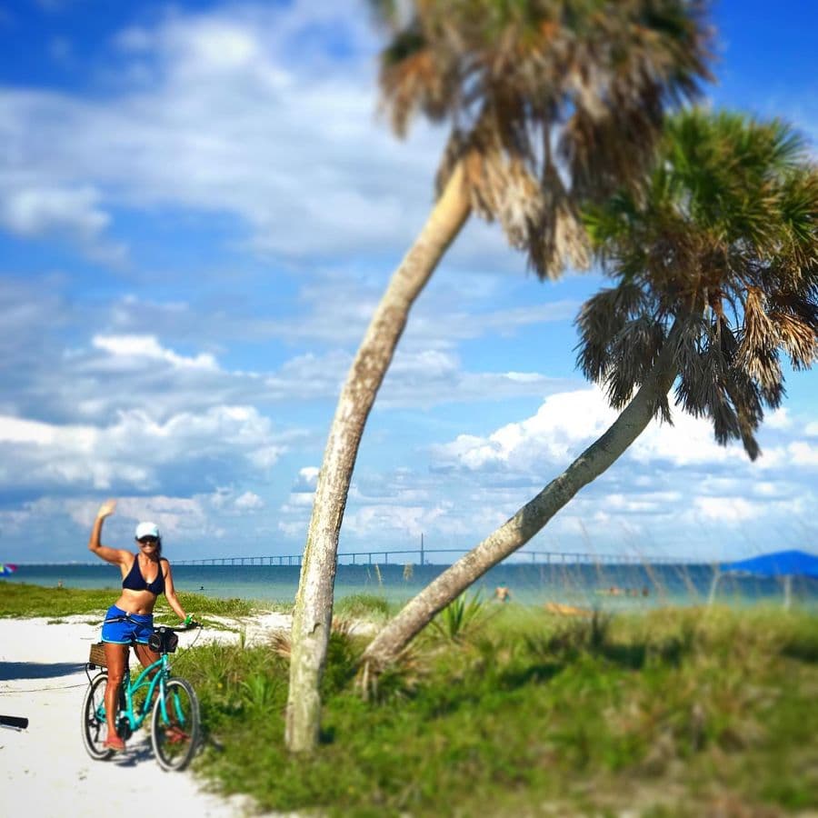 Jennifer waving from her bike on the beach path
