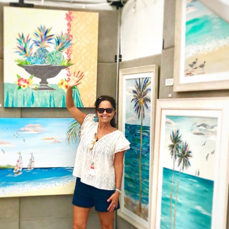 Jennifer waving inside the booth in front of the palm pieces