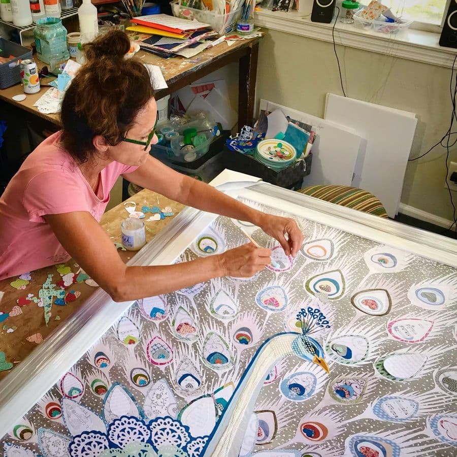 Jennifer placing cut paper on a peacock piece